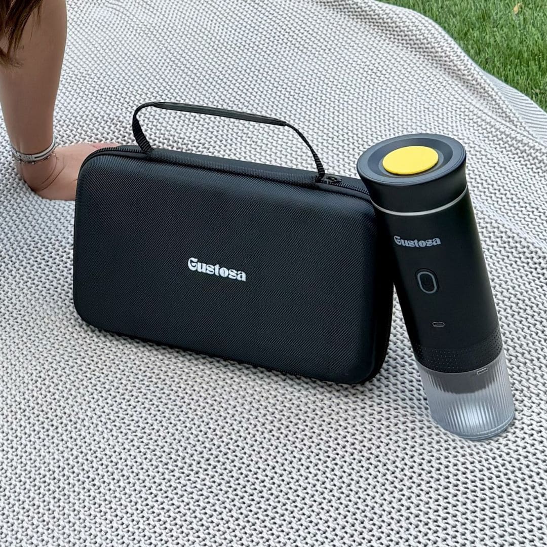 The Gustosa hard-shell carrying case and MyGustosa portable espresso maker placed side by side on a white knit blanket outdoors, showcasing the complete and compact travel coffee setup.