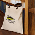 The Gustosa canvas shopper tote bag with dark brown handles leaning against a wooden staircase  displaying the brand slogan "Turns out, with Gustosa you can brew damn good coffee anywhere.